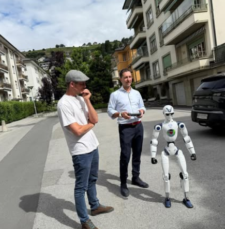 Two people are standing on a sidewalk, one holding a humanoid robot. Le contenu généré par l’IA peut être incorrect.